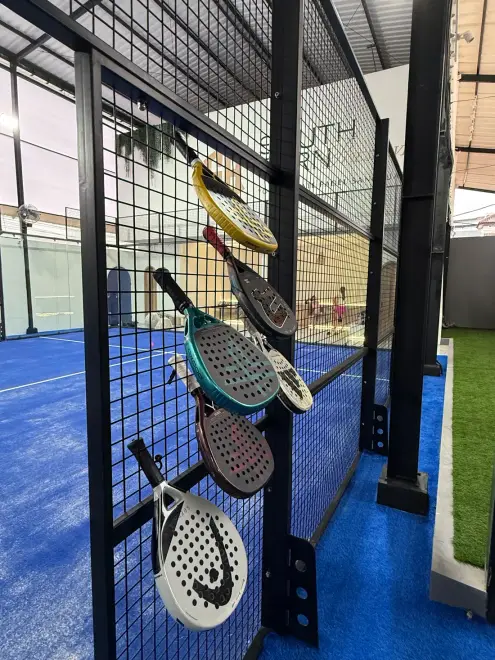 Padel rackets hanging on the court fence