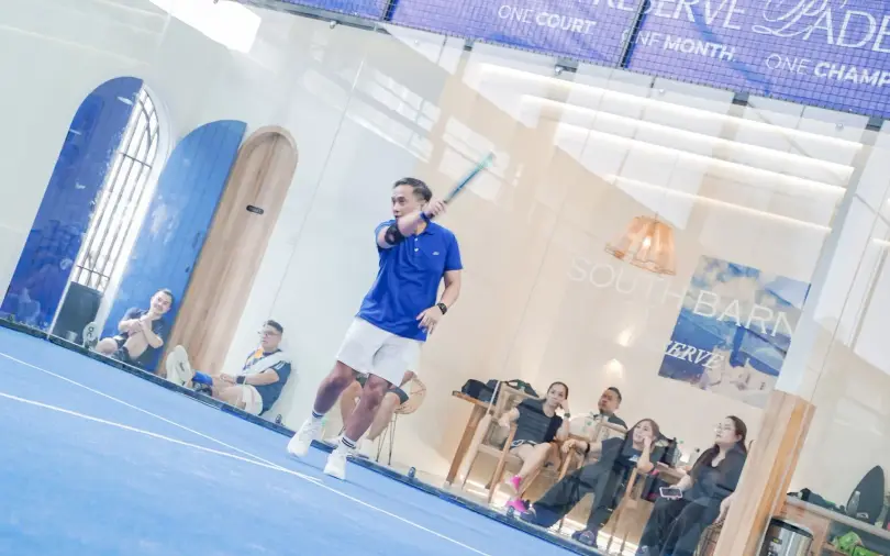 Lounge with arched blue doors and rattan lamps beside the court