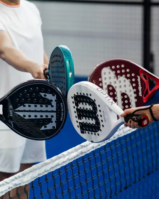Four padel rackets touching over the net